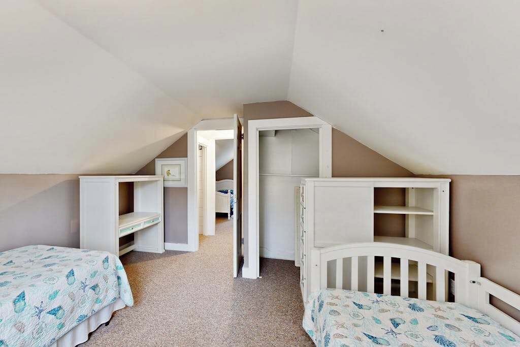 A child's bedroom with bunk beds, a small desk, and a walk-in closet.