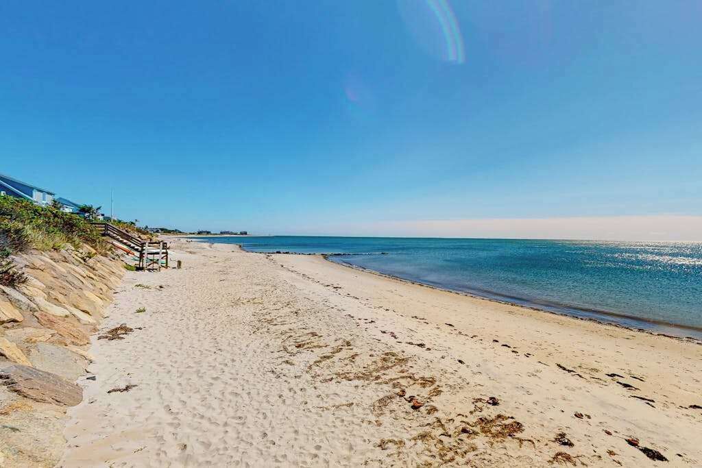 Une plage avec un ciel dégagé, un rivage sablonneux et une clôture en bois.