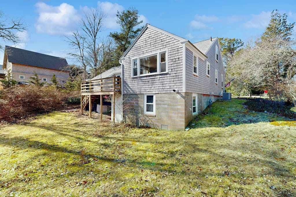 Une maison à deux étages avec une terrasse en bois et un petit porche.