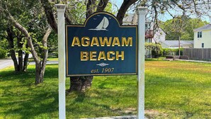 A sign for Agawam Beach with a sailboat graphic, established in 1907.