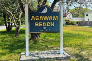 A sign for Agawam Beach with a sailboat graphic, established in 1907.