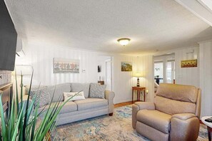 A living room with a sofa, armchair, and a rug.