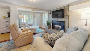 A living room with a fireplace, a sofa, a recliner, and a TV mounted on the wall.