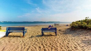 A beach with two benches, a sandy shore, and a clear sky. - Gorgeously rebuilt Cape Cod estate with lovely grounds, walk to private beach (West Yarmouth)