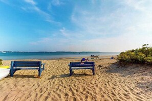 A beach with two benches, a sandy shore, and a clear sky. - Gorgeously rebuilt Cape Cod estate with lovely grounds, walk to private beach (West Yarmouth)