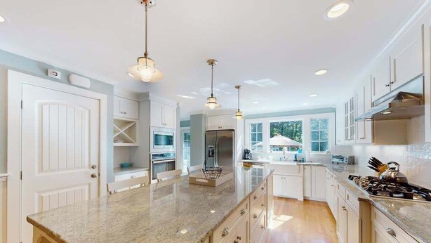 A modern kitchen with white cabinetry, granite countertops, and pendant lighting. - Gorgeously rebuilt Cape Cod estate with lovely grounds, walk to private beach (West Yarmouth)