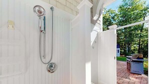 A white door with a showerhead, a white fence, and a grill in the background. - Gorgeously rebuilt Cape Cod estate with lovely grounds, walk to private beach (West Yarmouth)