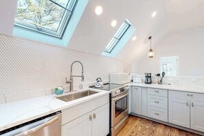 A modern kitchen with a skylight, white cabinetry, and a built-in oven.