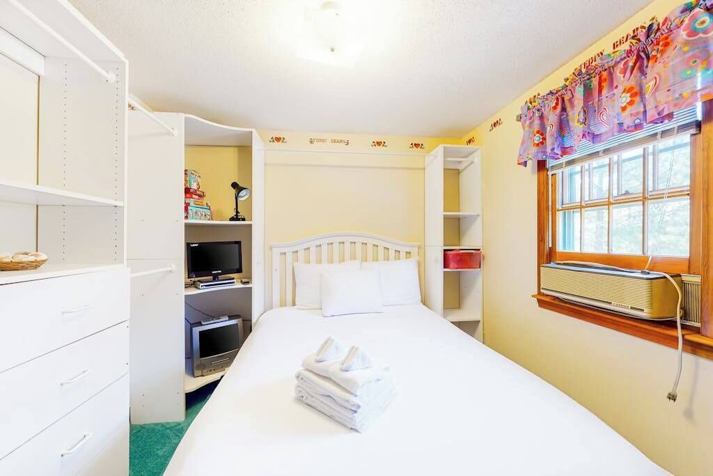 A hotel room with a bed, a TV, a wardrobe, and a window with a curtain.