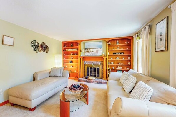 A living room with two sofas, a coffee table, a fireplace, and a bookshelf.