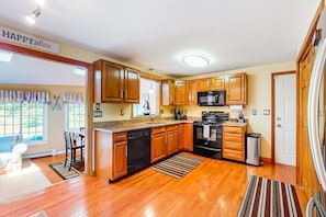 Una cocina con gabinetes de madera, lavavajillas, microondas y refrigerador.