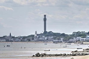 Eine Küstenstadt mit einem markanten Leuchtturm, einem Sandstrand und Booten.