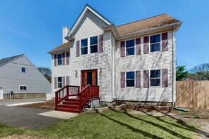 A two-story house with a front porch, a staircase, and a wooden fence.
