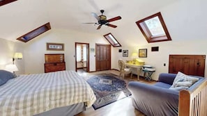 A bedroom with a bed, a chair, a desk, and a ceiling fan.