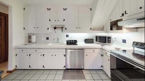 A modern kitchen with white cabinetry, a stainless steel dishwasher, a microwave, and an oven. - Gorgeous home near the ocean w/ a full kitchen, deck, & large, fenced back yard (Vineyard Haven)