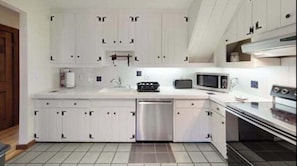 Una cocina moderna con armarios blancos, un lavavajillas de acero inoxidable, un microondas y un horno.
