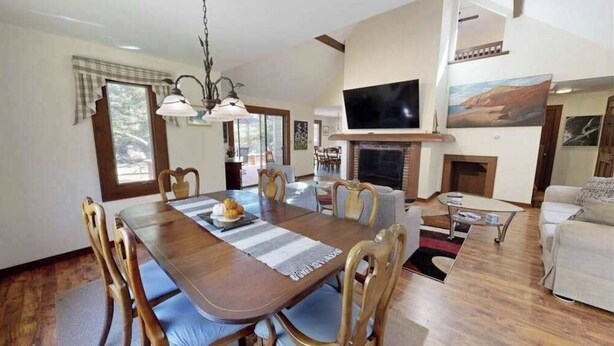 A spacious living room with a dining area, a fireplace, and a TV mounted on the wall. - Gorgeous home near the ocean w/ a full kitchen, deck, & large, fenced back yard (Vineyard Haven)