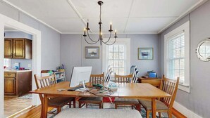 Ein Esszimmer mit Holztisch, Stühlen, einer Chandelüstere und Blick auf die Küche.