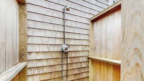 Eine Holzaußenwand mit einer Metallrohrleitung und einem Ventil, vermutlich Teil einer Wasserinstallation.
