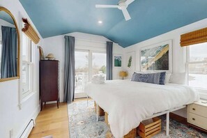 A bedroom with a bed, a ceiling fan, a dresser, and a window with curtains. - West End updated dog friendly home w/ firepit, AC & yard (Provincetown)