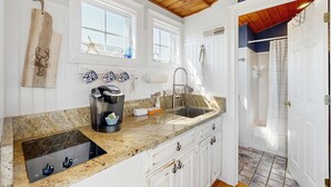 Une cuisine dotée de plans de travail en granit, d’une cuisinière encastrée, d’un évier et d’une fenêtre décorée de motifs d’étoiles de mer.