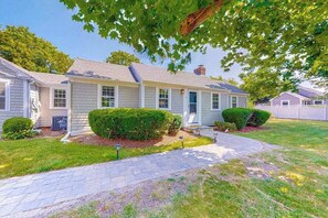 A two-story house with a front porch, a driveway, and a well-maintained lawn. - Captain Clark's | Renovated house in Yarmouth with large yard - close to beaches (Yarmouth)