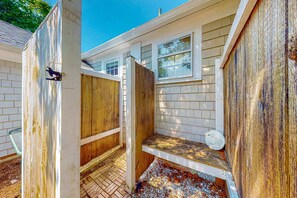 A small, enclosed outdoor bathroom with a wooden door, a window, and a bench. - Captain Clark's | Renovated house in Yarmouth with large yard - close to beaches (Yarmouth)