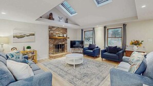 Ein geräumiges Wohnzimmer mit Kamin, blauen Sofas, einem Couchtisch und Dachfenstern.
