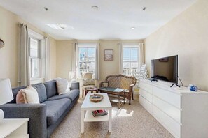 Sala de estar con sofá, mesa de centro, televisor y vistas al balcón.