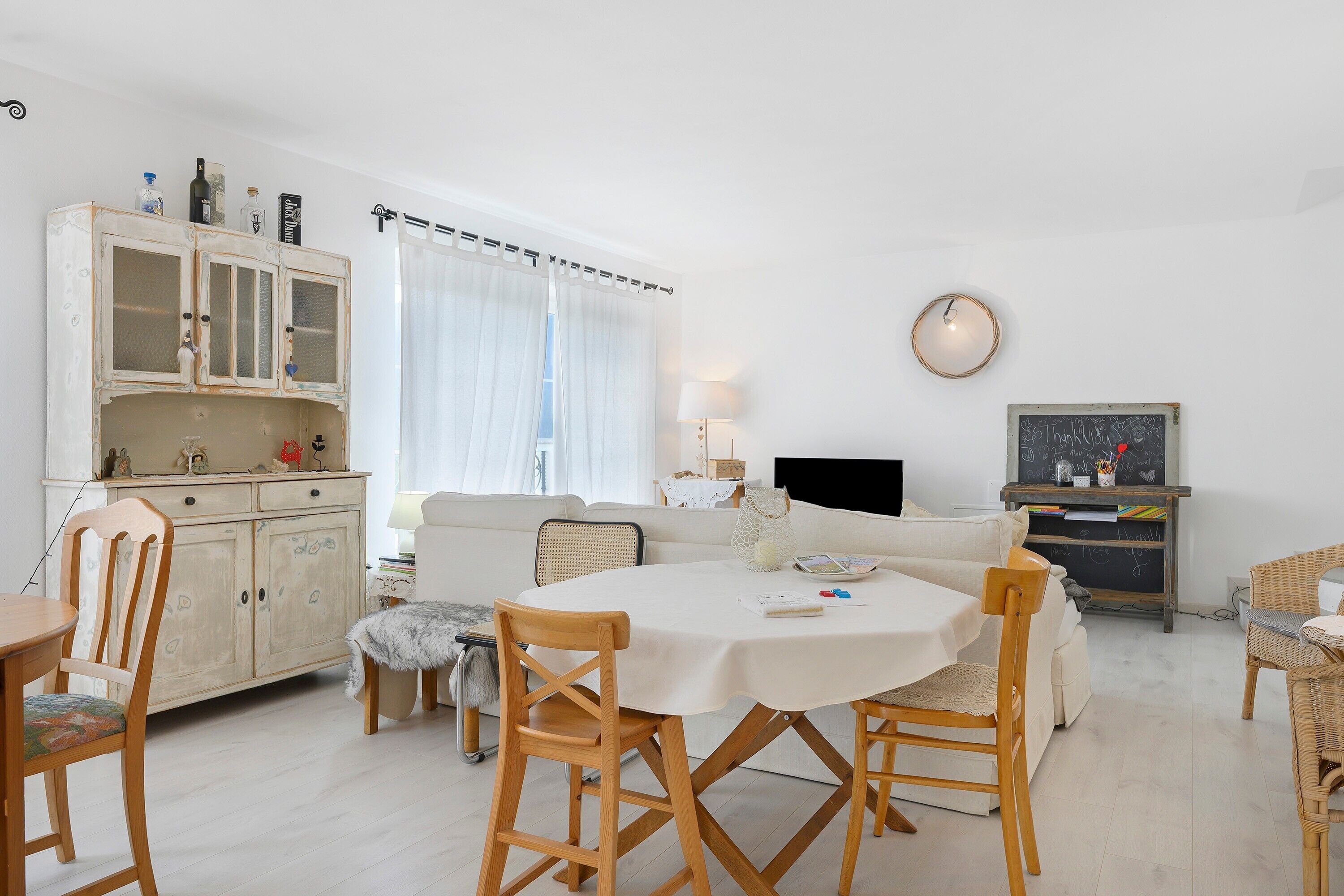 Un salon comprenant une table à manger, des chaises, un canapé, un meuble et un téléviseur.