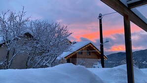 Paisaje nevado con una estructura de madera y una casa iluminada.