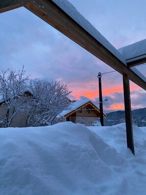 A snow-covered landscape with a wooden structure and a house with lights.