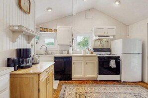 A kitchen with white cabinetry, a stove, a dishwasher, and a refrigerator.