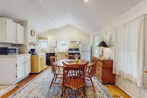 A compact kitchen with white cabinetry, a dining table with chairs, and a patterned rug.