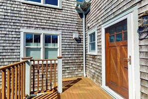 A wooden deck with a railing, a wooden door, and a window. - Charming condo with parking, washer/dryer, AC, and deck (Provincetown)