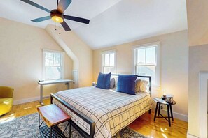 A bedroom with a bed, a desk, a chair, a ceiling fan, and a window. - Charming condo with parking, washer/dryer, AC, and deck (Provincetown)