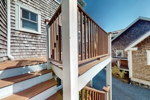 A residential property with a wooden deck, a white exterior, and a small window. - Charming condo with parking, washer/dryer, AC, and deck (Provincetown)
