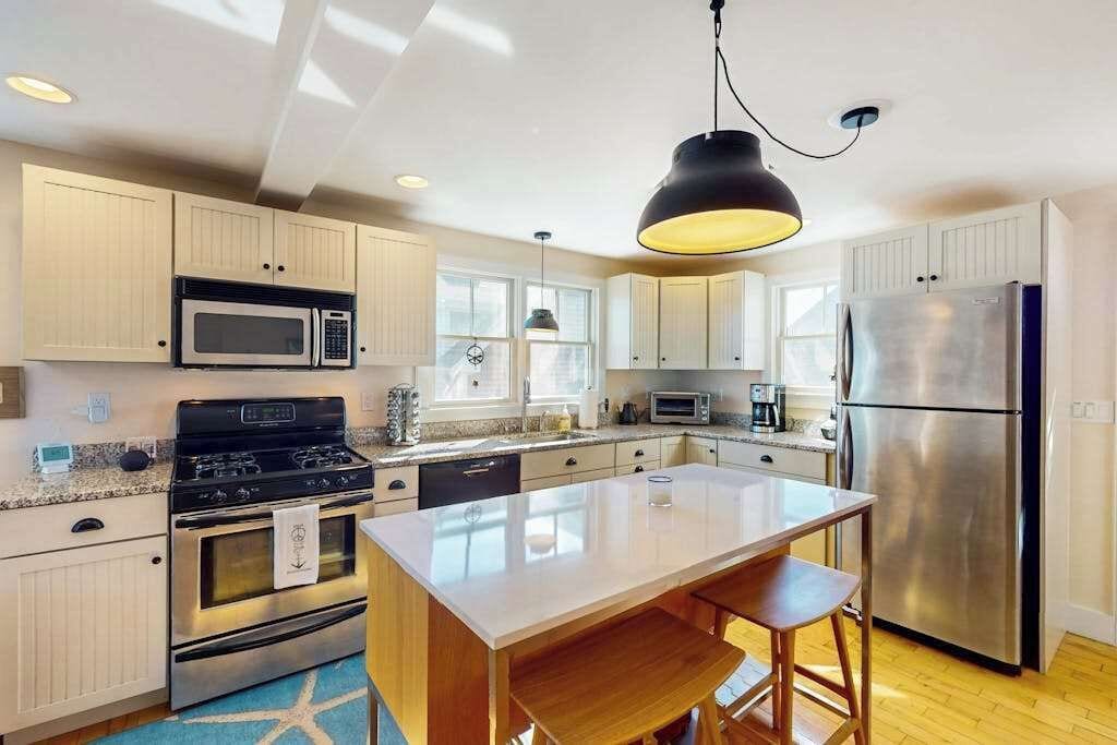 Een moderne keuken met een centraal eiland, roestvrijstalen apparatuur en lichtkleurige kastjes.