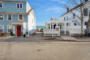 A coastal street with two-story houses, a red door, and a clear view of the ocean. - Cozy condo in great location with deck, board games, & AC (Provincetown)
