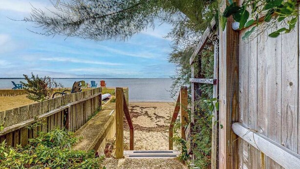 Une promenade en bois qui mène à une plage d’où l’on a une vue dégagée sur l’océan.