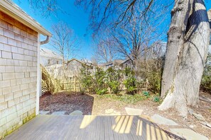 A wooden deck, a brick house, and a wooden fence in a backyard. - Charming, sunlit studio in the heart of town with fast WiFi (Provincetown)