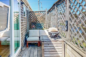 A wooden deck with a cushioned seating area, a small table, and a wooden fence. - Loft-style condo with private deck - near Truro Beach/Dune Shacks (Provincetown)