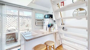 Une cuisine moderne dotée d’un îlot central, de tabourets de bar, d’un four à micro-ondes et d’un réfrigérateur.