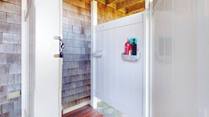A wooden exterior wall, a white door, and a small shelf with fire extinguishers.