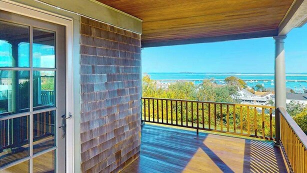 A covered balcony with a view of the ocean, a brick wall, and a wooden ceiling.
