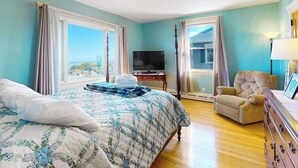 A bedroom with a bed, a TV, a chair, and a dresser.