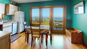 A compact kitchen with a dining area, a refrigerator, and a view through a sliding glass door.