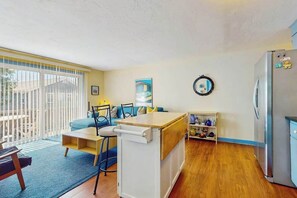 A compact living space with a kitchenette, a dining area, and a seating area with a view of the outdoors.