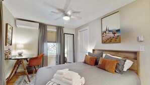 A bedroom with a bed, a desk, a chair, a ceiling fan, and a painting on the wall. - Cheerful condo with enclosed porch, next to Cape Cod Bay with beach access (Provincetown)