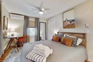 A bedroom with a bed, a desk, a chair, a ceiling fan, and a painting on the wall. - Cheerful condo with enclosed porch, next to Cape Cod Bay with beach access (Provincetown)